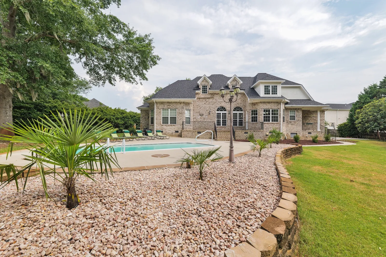Luxury brick estate with pool and lush landscaping